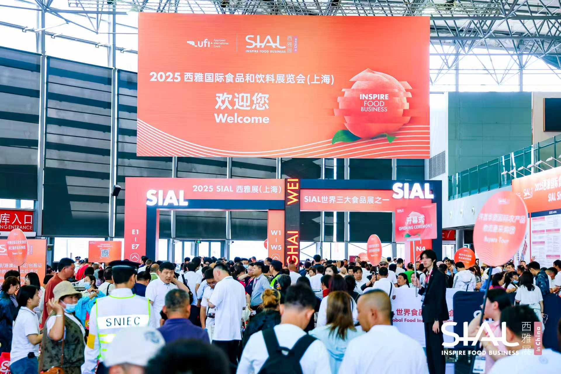 <img src="sial-shanghai-2025-exhibition-hall.jpg" alt="Crowded entrance of SIAL Shanghai 2025 exhibition with large orange welcome banner">