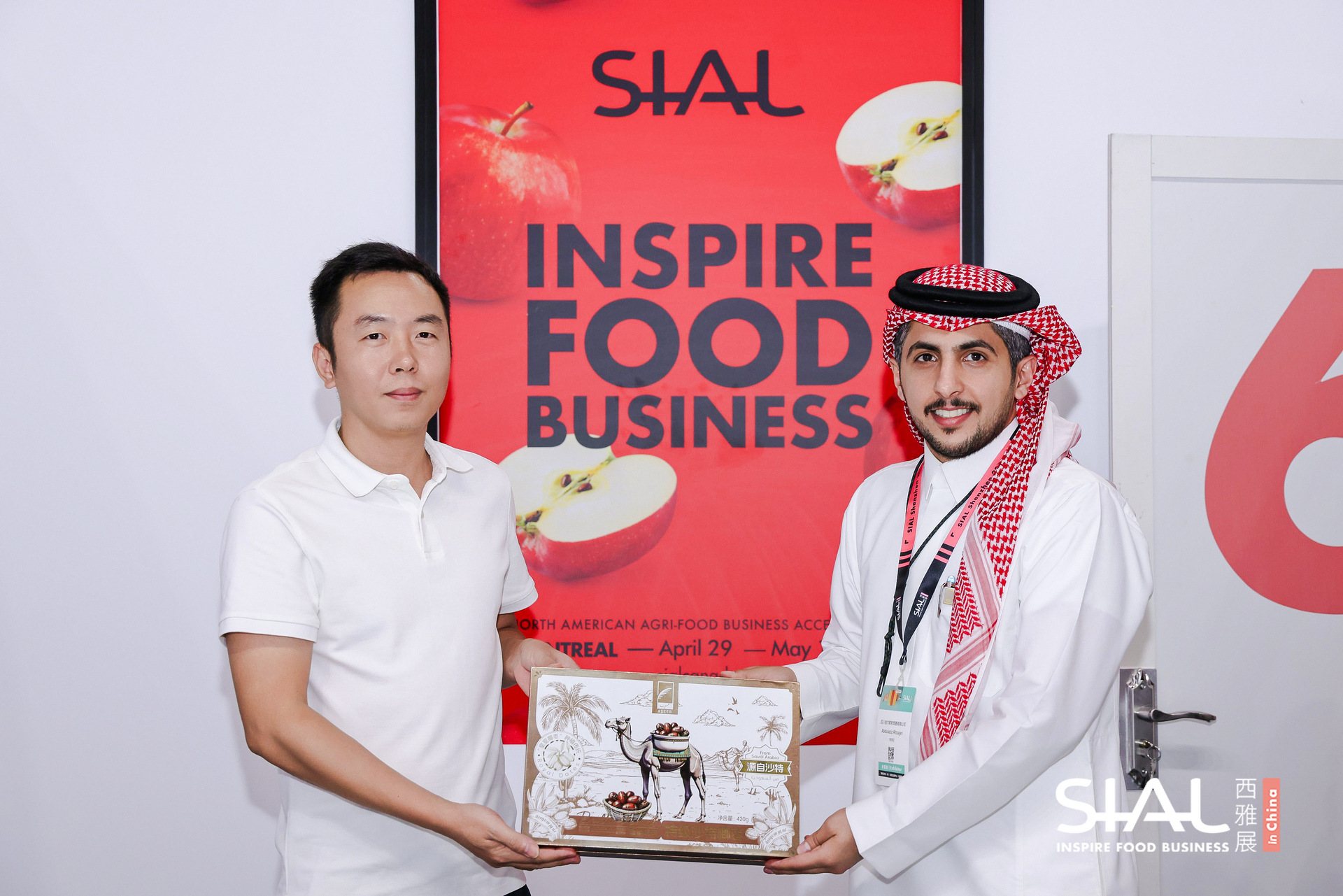 Two business representatives holding a gift box in front of a SIAL poster