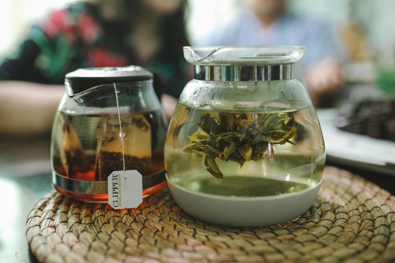 Close-up of glass teapots brewing herbal tea on a woven mat indoors