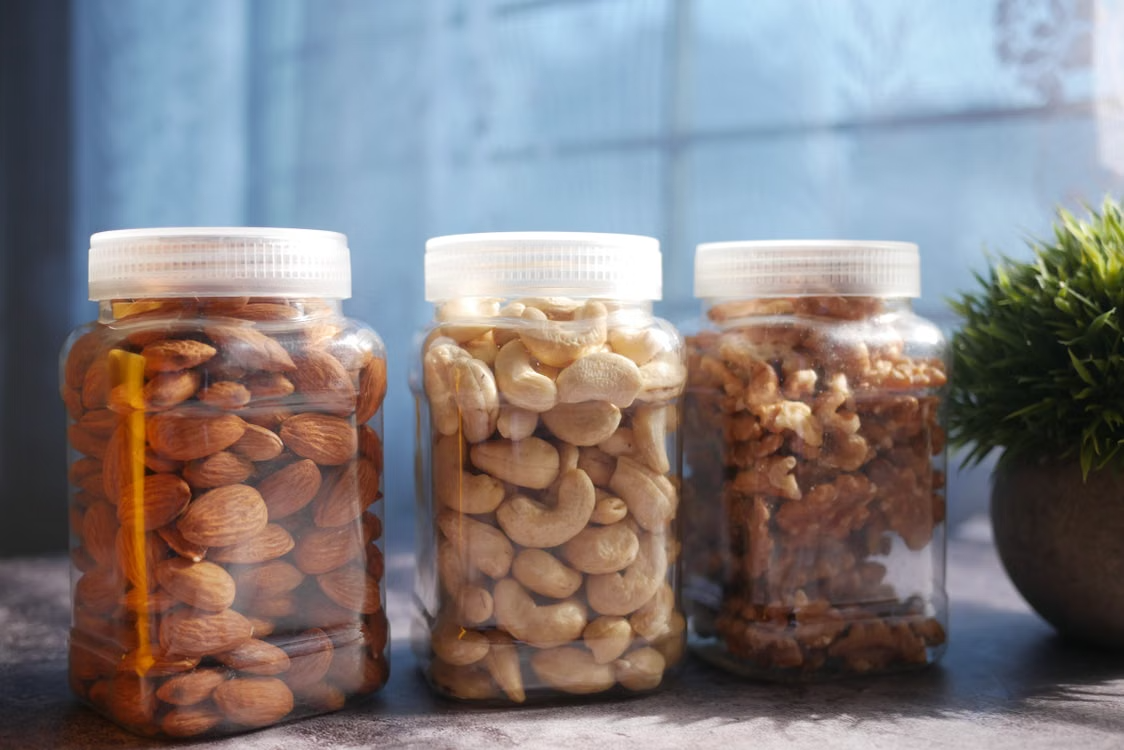 Vibrant display of almonds, cashews, and walnuts in plastic jars on a kitchen countertop